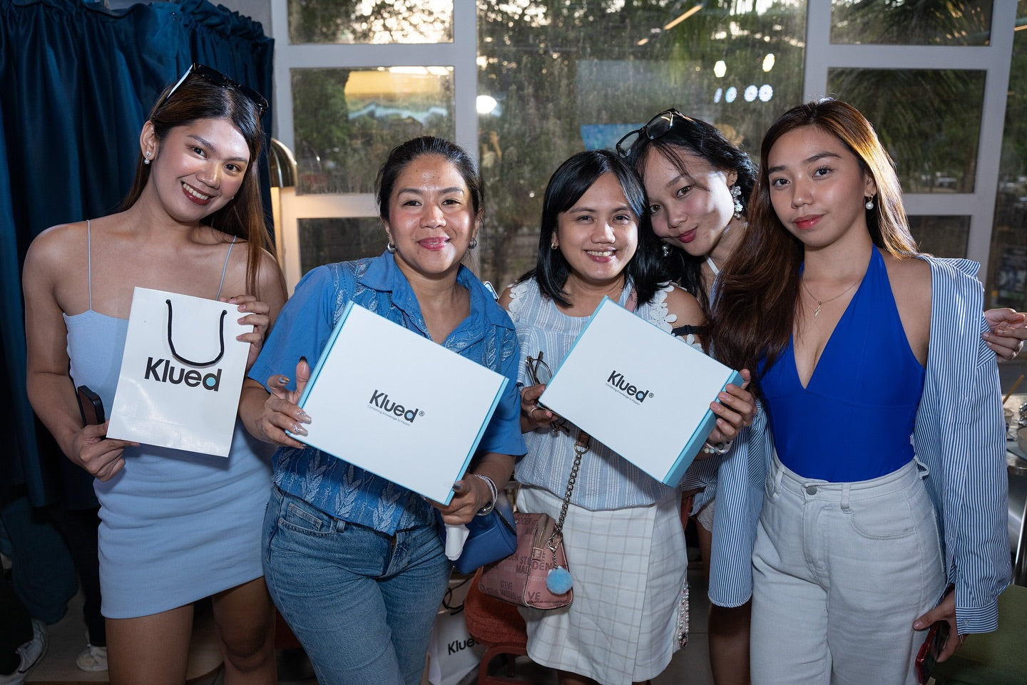 Five women holding Klued bags in an outdoor setting