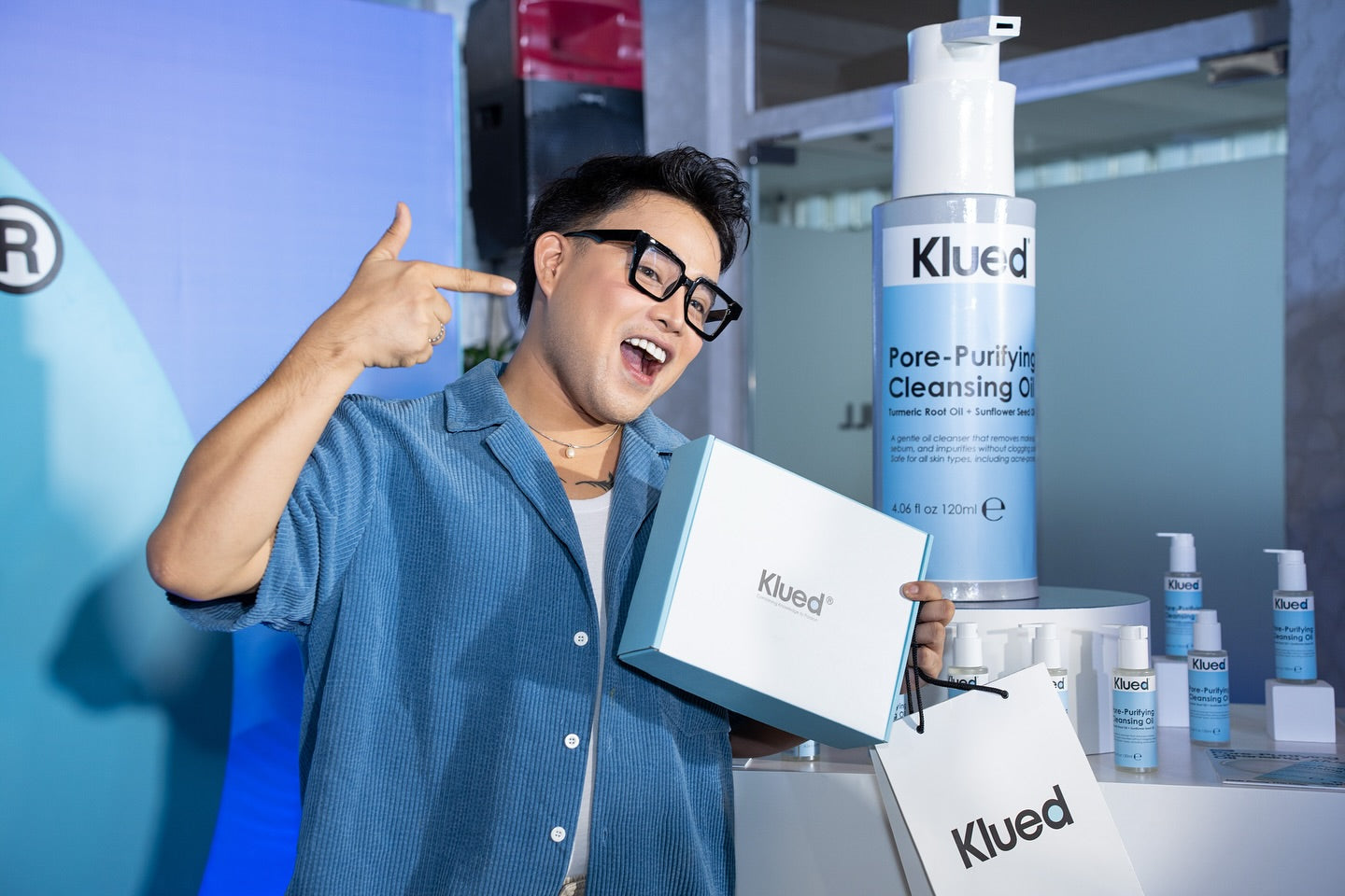 Person holding a Klued product box with various Klued skincare products in the background.