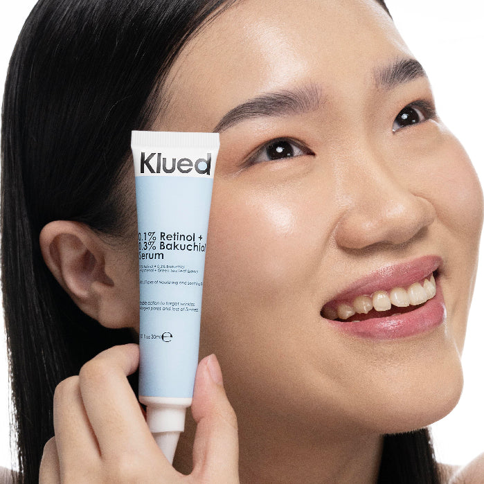 Woman holding a tube of Klued skincare product close to her face