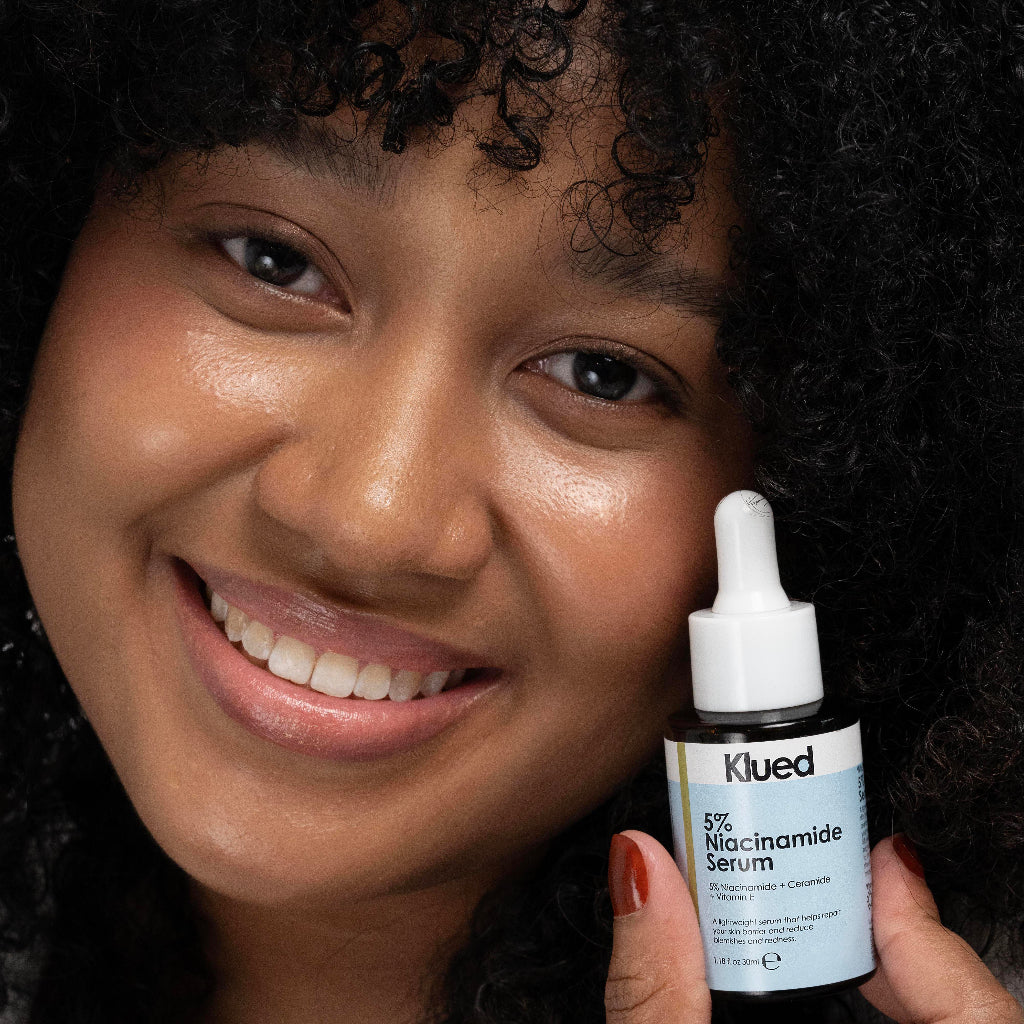 Woman holding a bottle of Klued 5% Niacinamide Serum close to her face