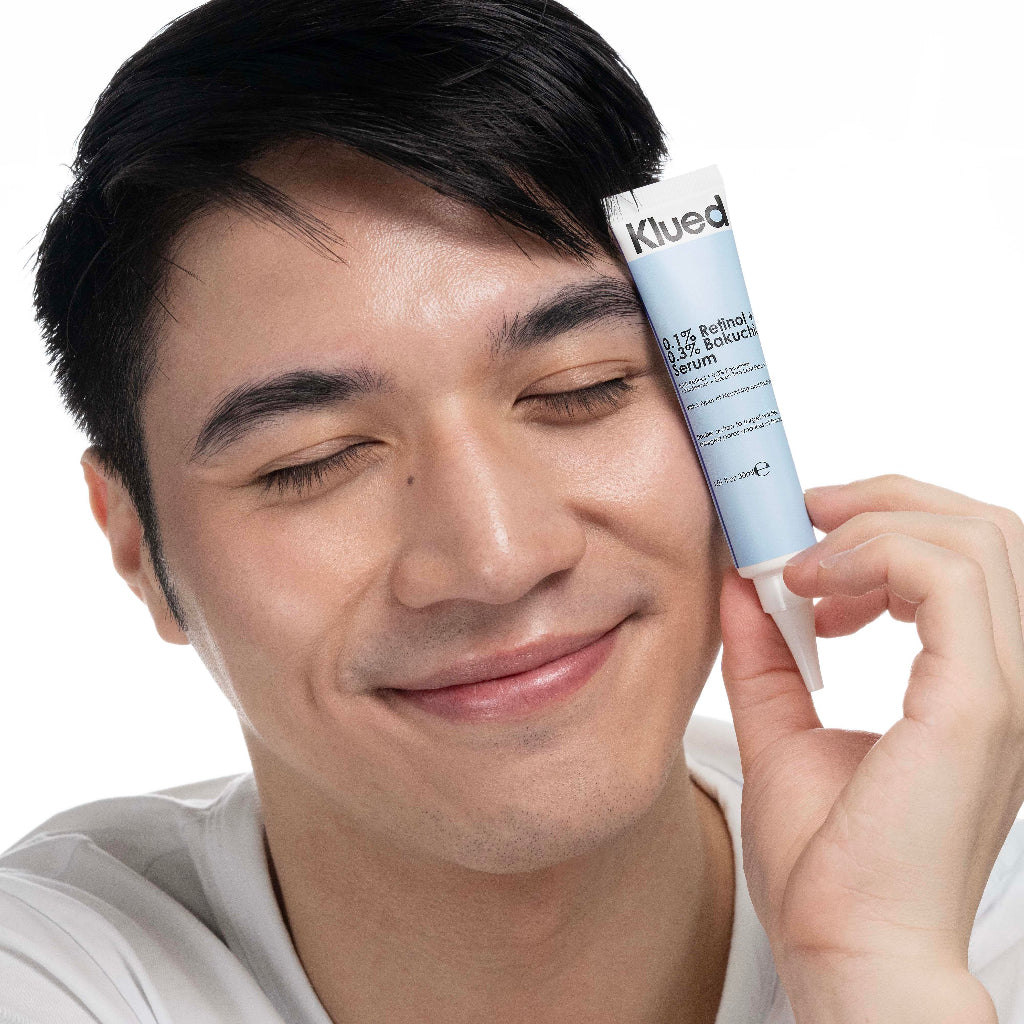 Man applying skincare product to his face with a tube labeled 'Klued' on a white background
