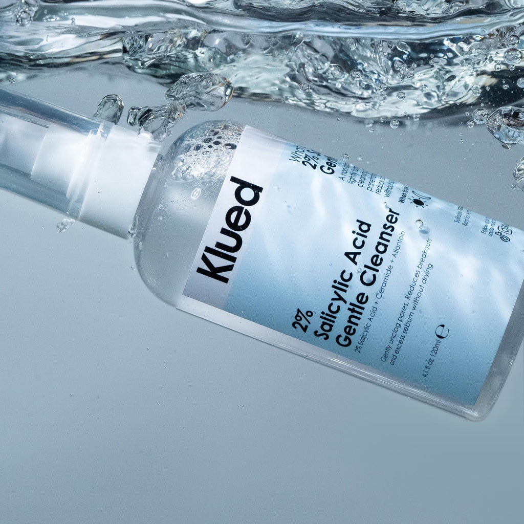 Klued 2% Salicylic Acid Gentle Cleanser bottle with water droplets on a gray background