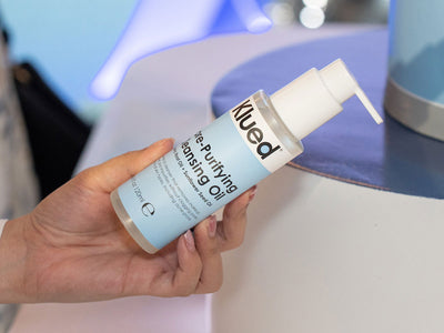 Hand holding a bottle of Klued Purifying Oil with a blurred background