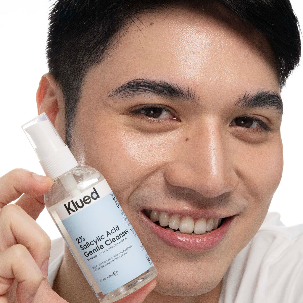 Person holding a bottle of Klued cleanser with a plain background