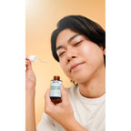 Person holding a bottle and dropper with a neutral background