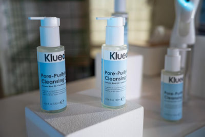 Three bottles of Klued Pore-Purifying Cleansing on a white surface with a blurred background.